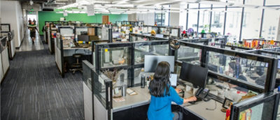  Office with woman working at desk in cubicle.