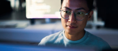Man working intently on a laptop in a modern office environment during evening hours.
