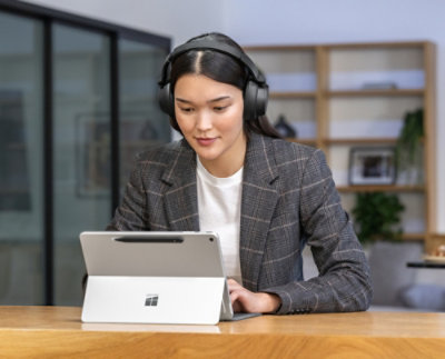 A woman wearing headphones and using a tablet.