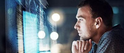 Person framför en datorskärm som visar kod.