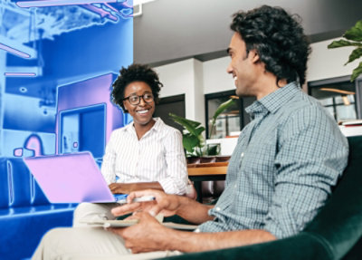 Ein Mann und eine Frau, die sitzen und auf einen Laptop blicken.