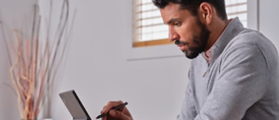 Ein Mann in grauem Hemd verwendet ein Tablet.