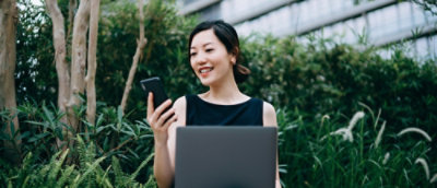 A person holding a phone and a laptop.