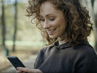 Eine Person mit schwarzem Hemd schaut auf ein Telefon.