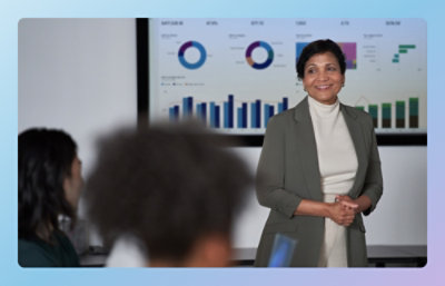 A woman smiling in front of a large screen.