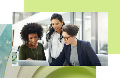 Drei Kollegen arbeiten an einem Laptop in einer modernen Büroumgebung zusammen.