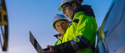 Zwei Personen mit Schutzhelmen und gelben Sicherheitswesten