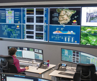 A person sitting at a desk in front of several monitors