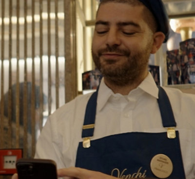 Eine Person, die eine blaue Schürze und eine Mütze mit der Aufschrift „Venchi“ trägt.