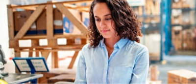 Person witha curly hair and a light blue shirt is standing in a warehouse 