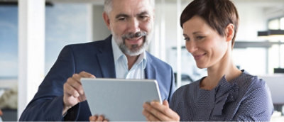 Two people in an office setting looking at a tablet.