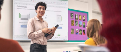 Osoba trzymająca tablet przed tablicą.