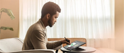 Mężczyzna siedzący przy stole i korzystający z laptopa.