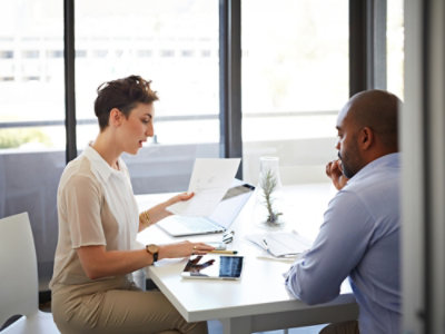 Un hombre y una mujer sentados en una mesa con documentos.