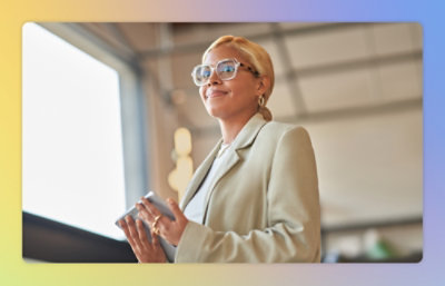 A woman wearing blazer holding a tablet and smiling