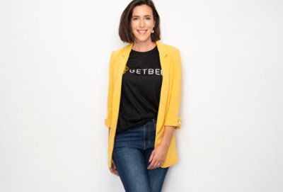 A person wearing a yellow jacket and blue jeans with the visible text GETBEE 