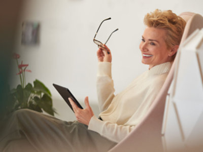 En person, der holder briller og en tablet