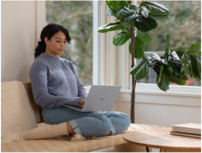 Eine Person, die auf einer Couch sitzt und einen Laptop nutzt.