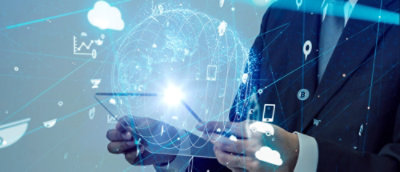 Businessman using a tablet with futuristic augmented reality graphics of global networks and data overlaid in the air in front of him.