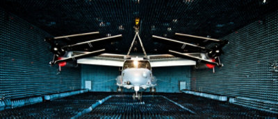 A helicopter undergoing testing inside an anechoic chamber covered with blue foam pyramidal sound absorbers.