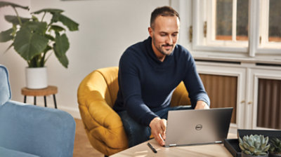 Osoba siedząca na krześle i używająca laptopa.