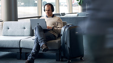 A person sitting on a couch using headphones and a laptop.