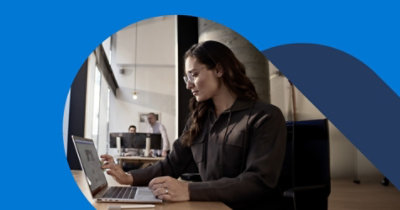 一个人在开放式办公室的办公桌上使用笔记本电脑工作