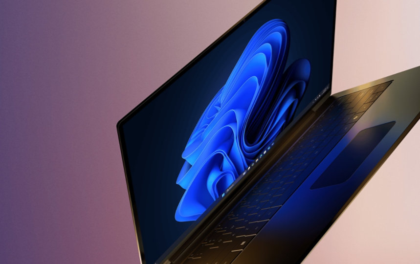 A modern, partially open laptop with the Microsoft blue bloom on home screen, set against a gradient background of purple and beige 