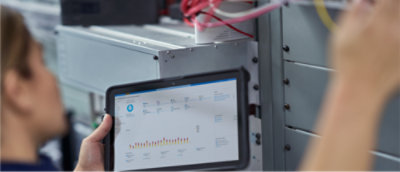 Person som håller i en surfplatta med diagram framför ett serverrack.