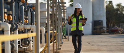 A woman in a hard hat is holding a tablet in her hand