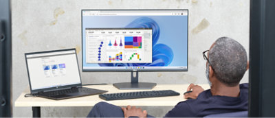 Osoba sedící v kanceláři a pracující s více počítači