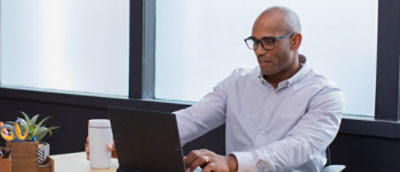 A man sitting at a desk using a laptop.