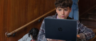 A boy looking at a laptop.