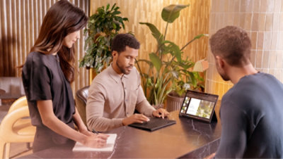 Three people in an office setting: one takes notes, another types on a keyboard