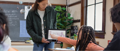 Una mujer con el pelo trenzado en una habitación con ventana, apuntando a una pantalla.