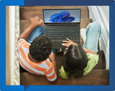 Dwoje dzieci siedzących na schodach i wspólnie używających laptopa. Na ekranie widoczny jest niebieski falisty wzór.