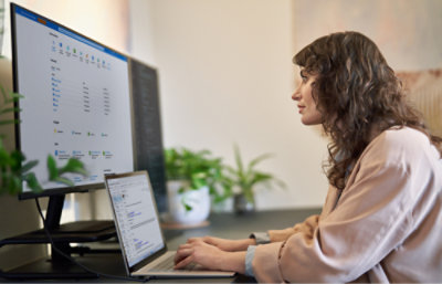 คนทำงานด้วยแล็ปท็อป ขณะดูจอภาพขนาดใหญ่ที่แสดงข้อมูลต่างๆ